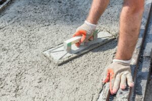 Hands using tool to smooth wet cement